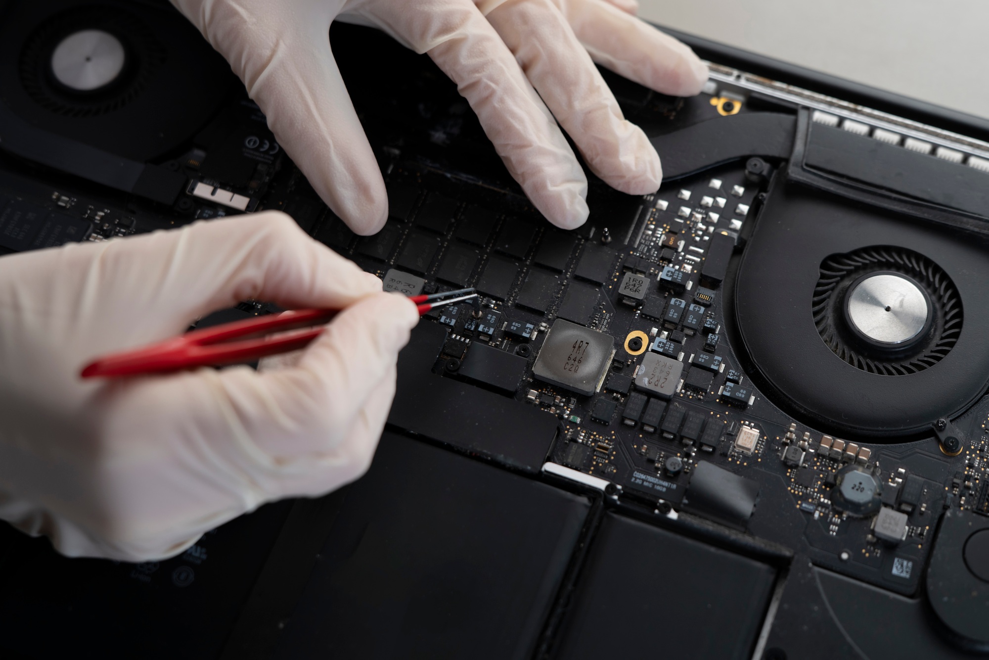 computer fixing service, master with tweezers repair laptop in the workshop